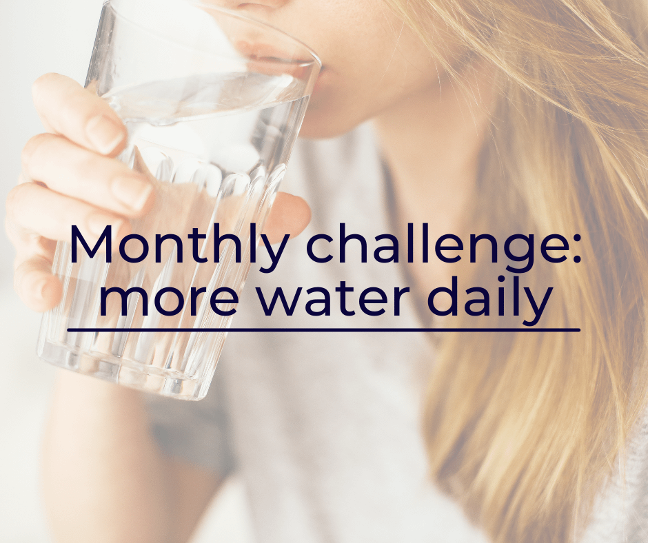 A close-up of a dark blond women in a while t-shirt drinking a glass of water